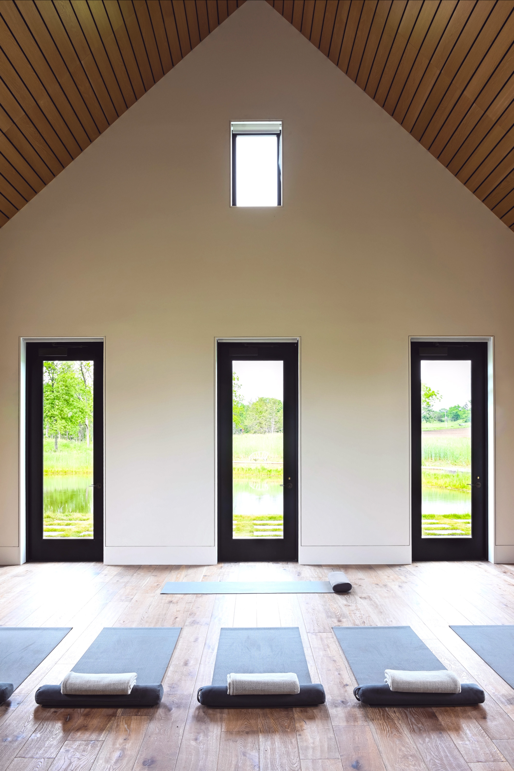 Calming yoga room with wooden floors and large windows.